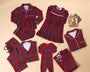 A collection of matching family Christmas pajamas, including Let Me Lounge Set - Society Prep Plaid with Worth Avenue White children’s sets and a girls’ nightgown, arranged around a copy of The Night Before Christmas book.