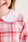A child wears The Beaufort Bonnet Company’s Lindy’s Lunch Dress in Broadway Play Plaid with Worth Avenue White, a long-sleeved plaid dress with a white rounded collar trimmed in pink.