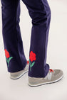 Patty Pants - Nantucket Navy & Richmond Red with Flowers in a navy blue bootcut style with embroidered flowers on the lower legs, worn with grey sneakers.