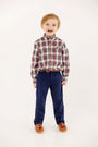 A young boy smiles wearing a Dean’s List Dress Shirt - Paris Pike Plaid with Nantucket Navy Stork, tucked into navy blue pants with a brown belt and brown loafers.