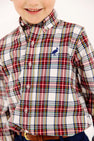 A child wears a Dean’s List Dress Shirt - Paris Pike Plaid with Nantucket Navy Stork, featuring a multi-colored pattern and a small dark blue stork icon embroidered on the chest.
