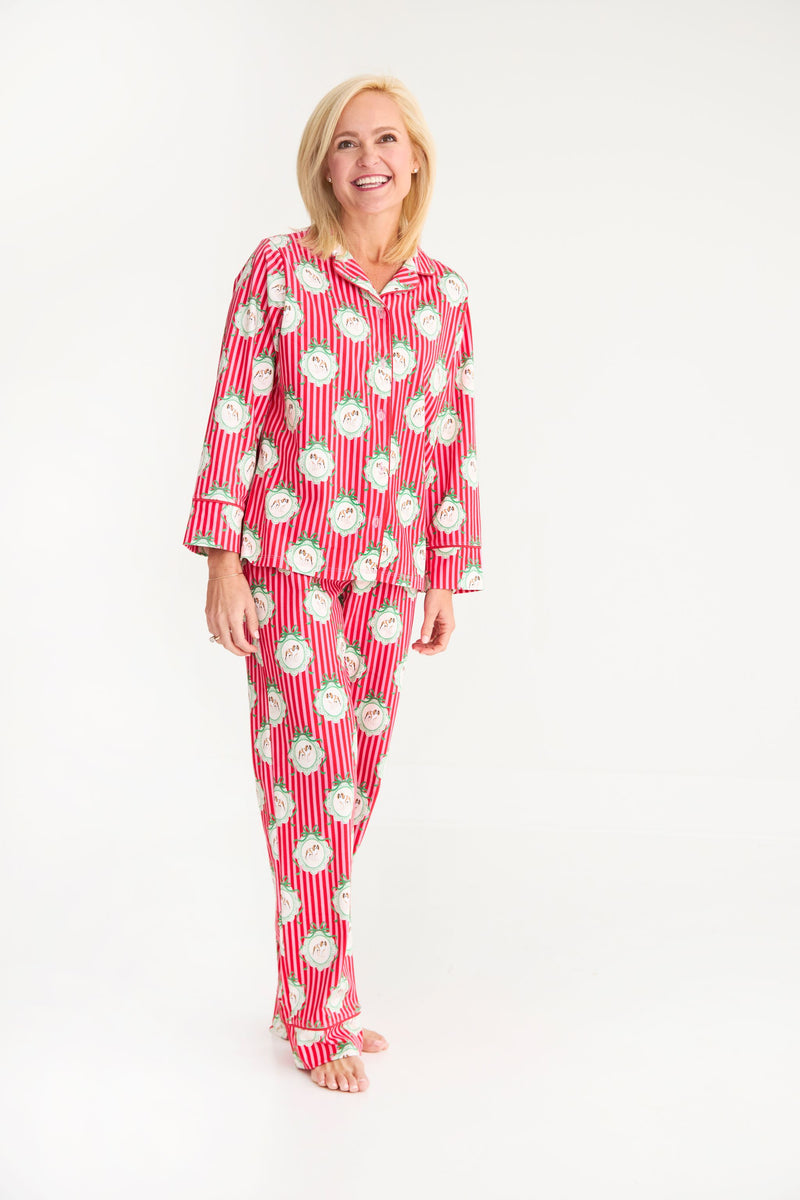 A woman wears a Let Me Lounge Set - Distinguished Doggies with Hamptons Hot Pink featuring a pattern of dogs in wreaths on a red and white striped background.
