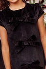 A girl wearing the Betts Bow Dress - Newport Night Velveteen, a holiday dress featuring three bows down the center front.