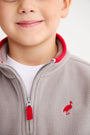 Close-up of a cozy gray Hayword Half-Zip (Fleece) - Grantley Gray with Richmond Red, featuring a red inner collar, red zipper pull, and a small red bird logo on the chest.