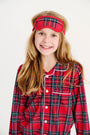 A smiling girl wears a Lock’s Little Set - Society Prep Plaid with Worth Avenue White red plaid pajama set with a matching sleep mask for the holidays.