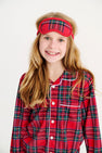 A smiling girl wears a Lock’s Little Set - Society Prep Plaid with Worth Avenue White red plaid pajama set with a matching sleep mask for the holidays.
