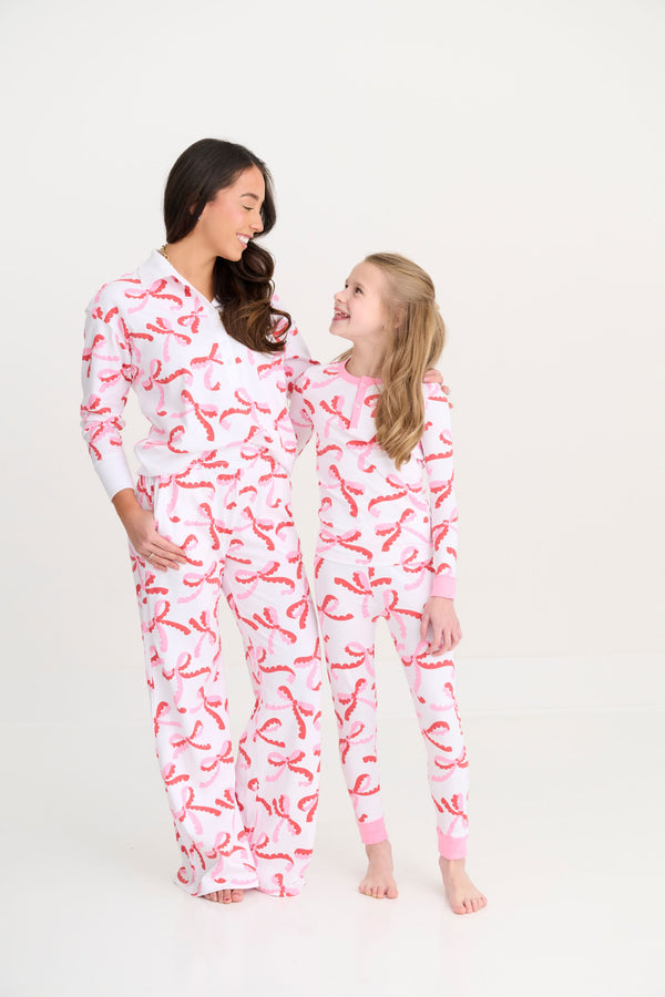 A woman and a young girl smile at each other while wearing matching Sara Jane’s Sweet Dream Set - Bonnie Scot Bows with Hamptons Hot Pink Pima cotton bow print pajamas.