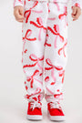 Child wearing cozy fleece-lined white Gates Sweeney Sweatpants - Bonnie Scot Bows with a red and pink bow print and red sneakers.