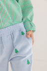 A child wearing a green checkered shirt and The Beaufort Bonnet Company’s Critter Sheffield Pants in Buckhead Blue Corduroy with embroidered Christmas Trees puts one hand in their pocket.