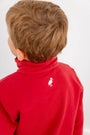 A young child with light brown hair wears The Beaufort Bonnet Company’s USC Hayword Half-Zip in South Carolina Burgundy with Worth Avenue White, featuring a white bird logo near the collar on the back that showcases classic Gamecock style. The child is turned slightly to the side, facing away from the camera.