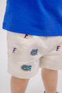 A child wearing The Beaufort Bonnet Company Florida Critter Sheffield Shorts - Saratoga Stone, paired with a blue shirt. The image highlights the lower back and legs, showing only part of the shirt and the kids’ gameday shorts.