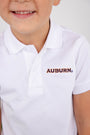A smiling child wears The Beaufort Bonnet Company’s Auburn Prim & Proper Polo in Worth Avenue White, crafted from soft Pima cotton and featuring the embroidered Auburn logo in orange and blue letters.