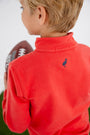 A child with blond hair, seen from behind, wears The Beaufort Bonnet Company’s Ole Miss Hayword Half-Zip in Ole Miss Red with Nantucket Navy—featuring an embroidered blue bird logo on the back—and holds an American football, making it the perfect game day layering piece.