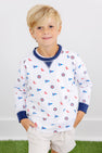 A young blonde boy is wearing The Beaufort Bonnet Company’s Ole Miss Cassidy Comfy Crewneck - Gawsh Almighty with Nantucket Navy, paired with beige shorts. He stands with his hands in his pockets and smiles at the camera against a plain background.