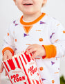 A young child is smiling and showing off their Clemson Orange spirit while wearing The Beaufort Bonnet Company’s “Clemson Cassidy Comfy Crewneck - Tiger Triumph with Clemson Orange,” and holding a red and white striped popcorn container.