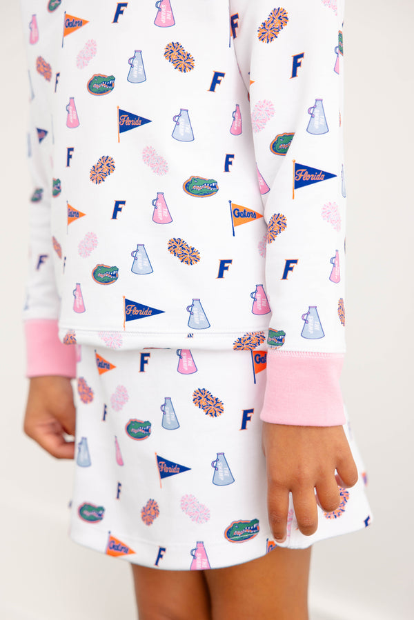 A child is shown from the torso down, wearing The Beaufort Bonnet Company’s Florida Searcy Skort in the colorful Florida Forever print with Worth Avenue White. Only one hand and part of the skort are visible against a plain background.