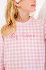 A child wears a Cassidy Comfy Crewneck - Palm Beach Pink Gingham with Hamptons Hot Pink Big Sister, a pink and white gingham sweatshirt embroidered with hot pink lettering for a sibling reveal outfit.