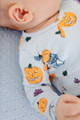 A baby wearing The Beaufort Bonnet Company’s Long Sleeve Patton Play Bubble - Candy & Critters (Buckhead Blue), lying on a textured light blue blanket.