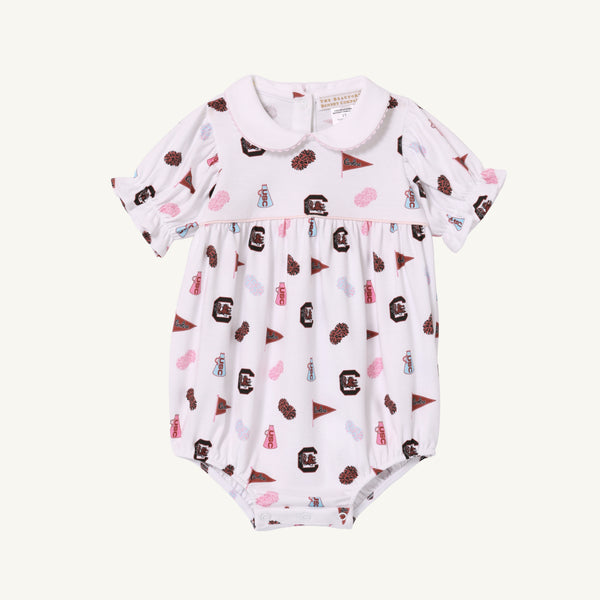 The Beaufort Bonnet Company’s USC Britt Bubble - South Carolina Spirit with Palm Beach Pink is a white baby romper with short sleeves and a Peter Pan collar, crafted from soft Pima Cotton. It features an all-over print of maroon, pink, and brown sports-related icons—including pennants, foam fingers, and megaphones—for a charming display of South Carolina Spirit.