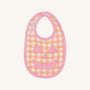 A fall baby essential, the Burp Me Bib - Seashore Sherbet Gingham & Hamptons Hot Pink by The Beaufort Bonnet Company features an orange and white gingham pattern with a hot pink trim and a cheerful pink jack-o-lantern face design on the front.