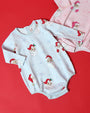 Two Long Sleeve Patton Play Bubble - Dear Santa (Buckhead Blue Stripe) rompers featuring a Santa Claus and snowflake pattern, one in blue stripes and one in pink stripes, against a red background.