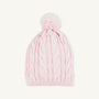 The Collins Cable Knit Hat in Palm Beach Pink from The Beaufort Bonnet Company features a classic cable knit pattern throughout and is topped with a large pompom. This girls’ winter hat is displayed against a plain white background.