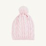 The Collins Cable Knit Hat in Palm Beach Pink from The Beaufort Bonnet Company features a classic cable knit pattern throughout and is topped with a large pompom. This girls’ winter hat is displayed against a plain white background.