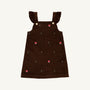 The Beaufort Bonnet Company Critter Julia Jumper in Chelsea Chocolate corduroy features ruffled shoulder straps, gold buttons, and small embroidered red fox faces with green plants scattered across the fabric.