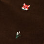 A close-up of The Beaufort Bonnet Company Critter Julia Jumper in Chelsea Chocolate corduroy, showcasing the fox embroidery—a red fox head alongside a delicate patch of white flowers with green stems.