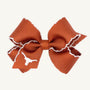 Show your Longhorn spirit with the Wee Ones Hair Bow - University of Texas by The Beaufort Bonnet Company. This burnt orange hair bow features a white stitched trim and a white longhorn outline on one end, all set against a plain light background. The perfect Game Day accessory for any University of Texas fan!.