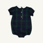 A Bedford Bubble - Berwick Black Watch baby romper by The Beaufort Bonnet Company, featuring a dark green and navy plaid pattern with Worth Avenue White & Nantucket Navy bows, puffed short sleeves, white buttons, a white collar, and elastic leg openings, displayed on a plain background.