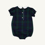 A Bedford Bubble - Berwick Black Watch baby romper by The Beaufort Bonnet Company, featuring a dark green and navy plaid pattern with Worth Avenue White & Nantucket Navy bows, puffed short sleeves, white buttons, a white collar, and elastic leg openings, displayed on a plain background.
