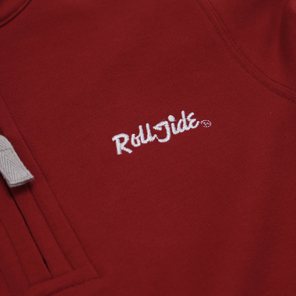Close-up of The Beaufort Bonnet Company’s Alabama Hayword Half-Zip in Alabama Crimson with Alabama Grey and Worth Avenue White, featuring “Roll Tide” embroidered in white cursive letters—perfect for game day layering. A portion of the light gray drawstring is visible on the left side of the image.