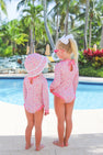 Two young girls in matching Sarasota Surf Suits (UPF 35+) - Mableton Mini Floral (Pink) with Romany Rose by The Beaufort Bonnet Company stand by a pool. One wears a sunhat, and the other has a white bow in her hair. Palm trees and lush greenery are visible in the background, highlighting their stylish swimwear from The Beaufort Bonnet Company.