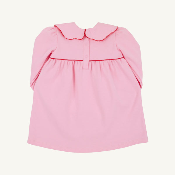 The Beaufort Bonnet Company’s Long Sleeve Maude’s Day Dress in Pier Party Pink with Richmond Red is a baby dress crafted from 100% Pima Cotton, featuring a scalloped collar, red trim, button closures on the upper back, and gentle gathering below the yoke.