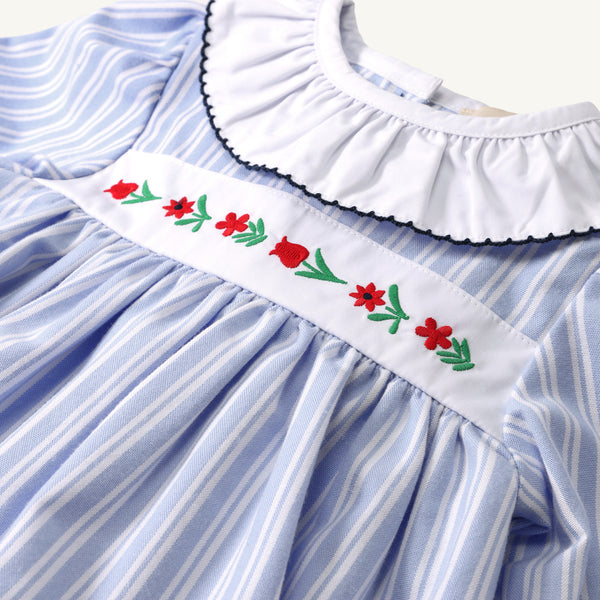 Long Sleeve Dollie Mae Dress - Park City Periwinkle Ticking Stripe & Worth Avenue White featuring a light blue and white striped pattern, a white ruffled collar, and an embroidered floral chest panel with red flowers and green stems.