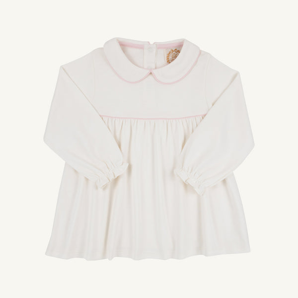 Maude’s A Line Top by The Beaufort Bonnet Company in Palmetto Pearl & Palm Beach Pink is a long-sleeve white baby top crafted from soft Pima cotton, featuring a Peter Pan collar with light pink trim on the collar and chest, gathered waist, back buttons, and elastic cuffs.
