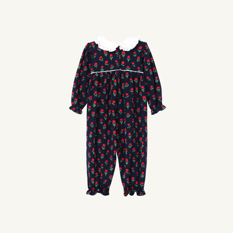 Maude’s Ruffle Romper - Prescott Farm Flowers with Worth Avenue White is a navy blue baby girl romper with a red floral print, featuring a white ruffled collar and ruffled sleeve cuffs.