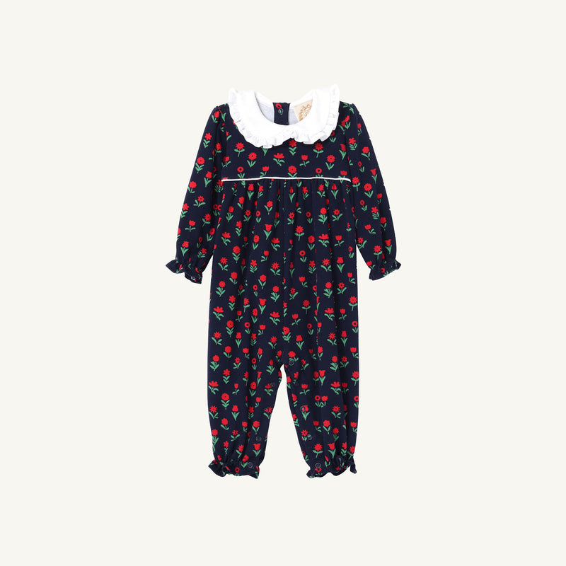 Maude’s Ruffle Romper - Prescott Farms Flowers with Worth Avenue White is a navy blue baby girl floral romper with a white ruffled collar, long sleeves, and ruffled cuffs.