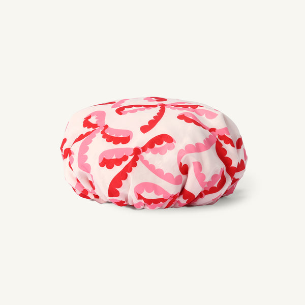Pamper Party Shower Cap - Bonnie Scot Bows featuring a pink background with a repeating pattern of red and pink scalloped bows.