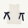 Introducing the Shae Sweater Vest - Palmetto Pearl with Nantucket Navy by The Beaufort Bonnet Company: a sleeveless white knit vest with ribbed edges, adorned with two navy blue ribbon bows tied at the sides. Made from 100% cotton, this sweater is a charming addition to any girl’s autumn wardrobe.
