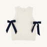Introducing the Shae Sweater Vest - Palmetto Pearl with Nantucket Navy by The Beaufort Bonnet Company: a sleeveless white knit vest with ribbed edges, adorned with two navy blue ribbon bows tied at the sides. Made from 100% cotton, this sweater is a charming addition to any girl’s autumn wardrobe.
