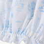 Sir Proper’s Sweet Arrival (Beale Street Blue) Bundle by The Beaufort Bonnet Company features white fabric adorned with light blue illustrations—including a stork carrying a bundle, trees, clouds, houses, and animals. This charming layette gown is gathered with elastic at the bottom edge and comes as part of an adorable everyday set with Bradley Bear, making it a thoughtful baby shower gift.