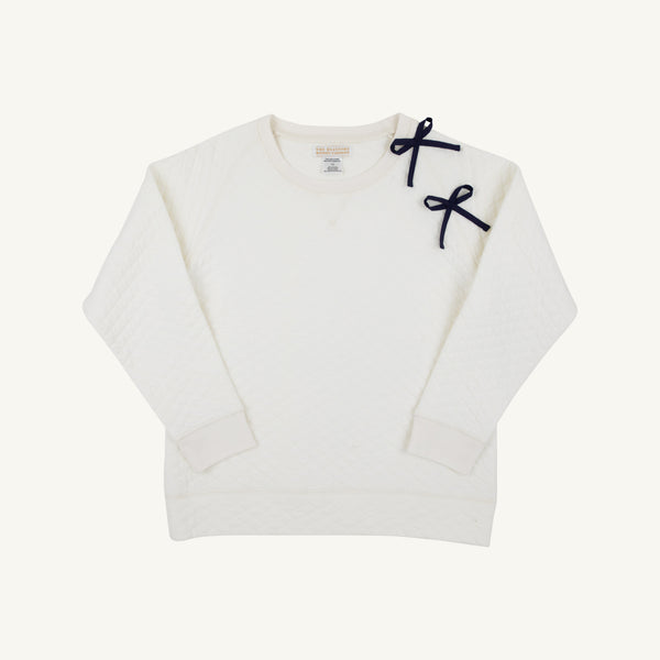 The Beaufort Bonnet Company’s Cassidy Comfy Crewneck – Quilted Palmetto Pearl with Nantucket Navy Bows – is a white quilted sweatshirt with long sleeves, ribbed cuffs and hem, and two small navy bows on the left shoulder, offering both style and comfort.