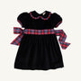 The Cindy Lou Sash Dress - Newport Night Velveteen with Bucktown Tartan by The Beaufort Bonnet Company is a delightful holiday dress for girls, crafted from soft velveteen and adorned with puffed short sleeves, a scalloped collar, and a large red, blue, and green Bucktown Tartan sash tied in a bow at the back—perfect for festive celebrations.