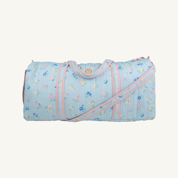 Introducing the Logan’s Long Weekend Bag by The Beaufort Bonnet Company, featuring the Little London Flowers print with charming pink gingham accents—a delightful light blue quilted carryall designed with practical handles and an adjustable shoulder strap, making it the perfect travel essential.