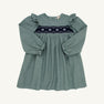 The Long Sleeve Daphne Dress in Grier Green Herringbone by The Beaufort Bonnet Company features ruffled shoulders and navy and white smocked floral embroidery across the chest, shown on a plain white background.