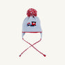 The Beaufort Bonnet Company Parrish Pom Pom Hat in Beale Street Blue features red and white pom-pom, earflaps, braided ties, and a delightful train motif on the front.