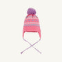 The Parrish Pom Pom Hat by The Beaufort Bonnet Company is a girls’ winter hat in Winter Park Pink, featuring a purple pom-pom, earflaps with braided strings, and a charming Fair Isle hearts pattern in light blue, white, and pink around the crown.