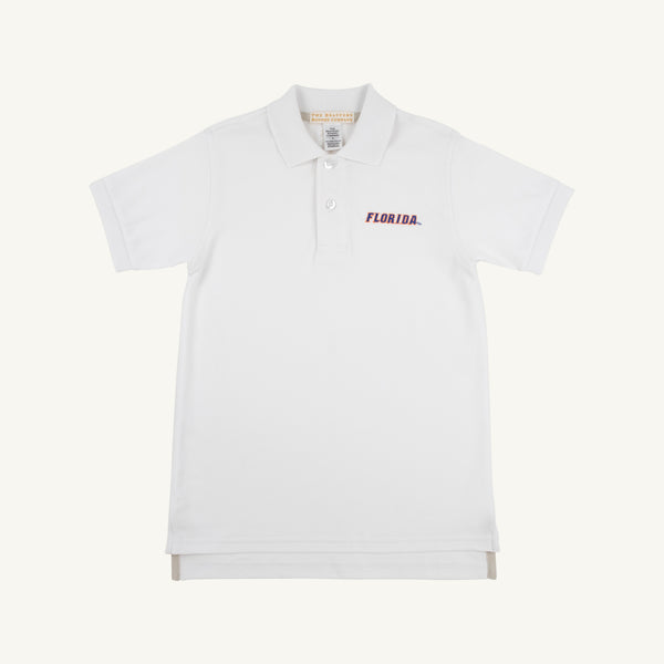 The Beaufort Bonnet Company’s Florida Prim & Proper Polo – Worth Avenue White is a short-sleeve, collared shirt with three buttons, made from soft Pima Cotton Knit. It features an embroidered red Florida logo on the left chest and is displayed against a plain off-white background.